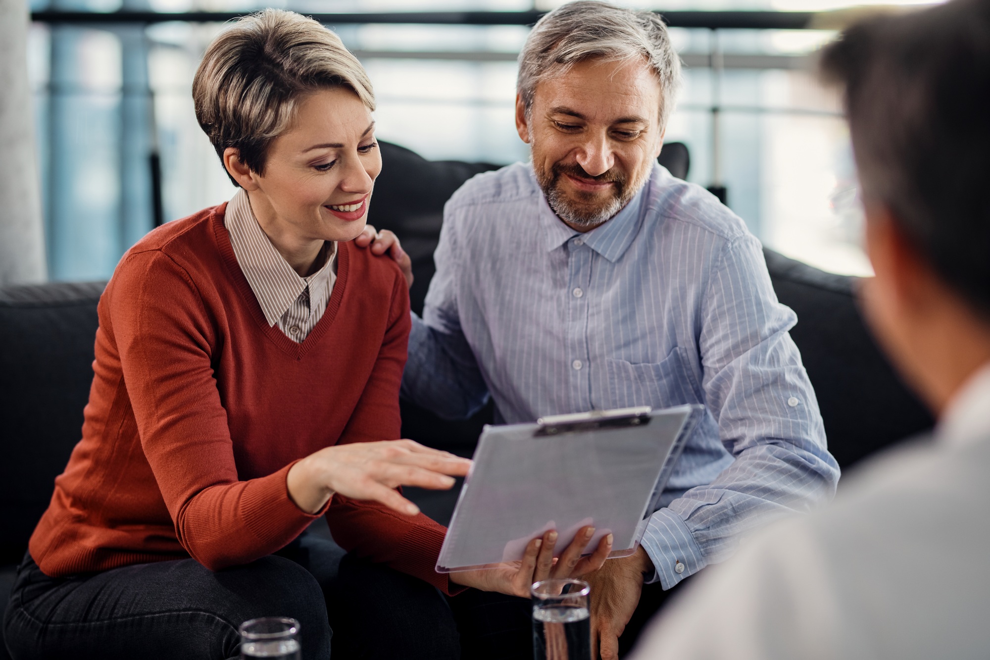 Happy couple going through terms of an agreement during a meeting with financial advisor.