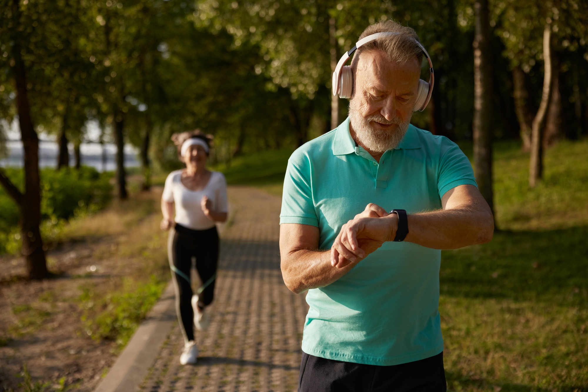 Senior man looking at wristwatch running in park